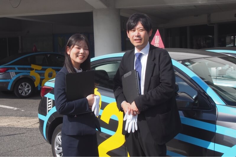 教習車の外に並んでいる講師2人の写真