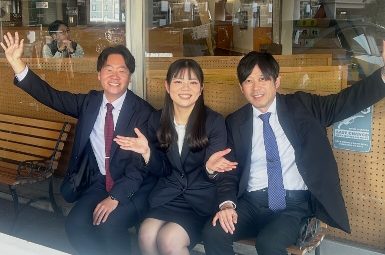 笑顔でベンチに座ってポーズをとっている3人の講師たちの写真