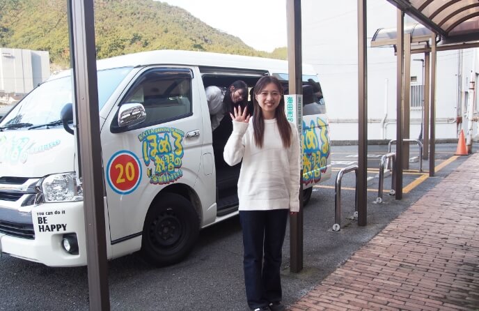 海田自動車学校の送迎車の前で手を振る在校生の写真