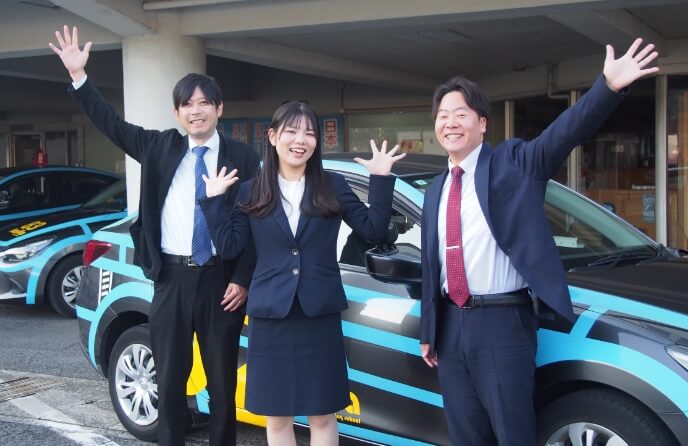海田自動車学校の3人の講師たちが笑顔でポーズを決めている写真