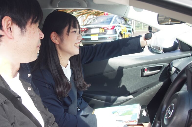 教習車の中で指導をしている講師とそれを聞いている在校生