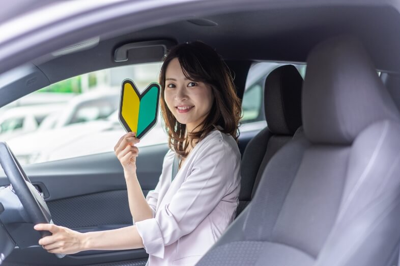 初心者マークを持って運転席に座っている女性