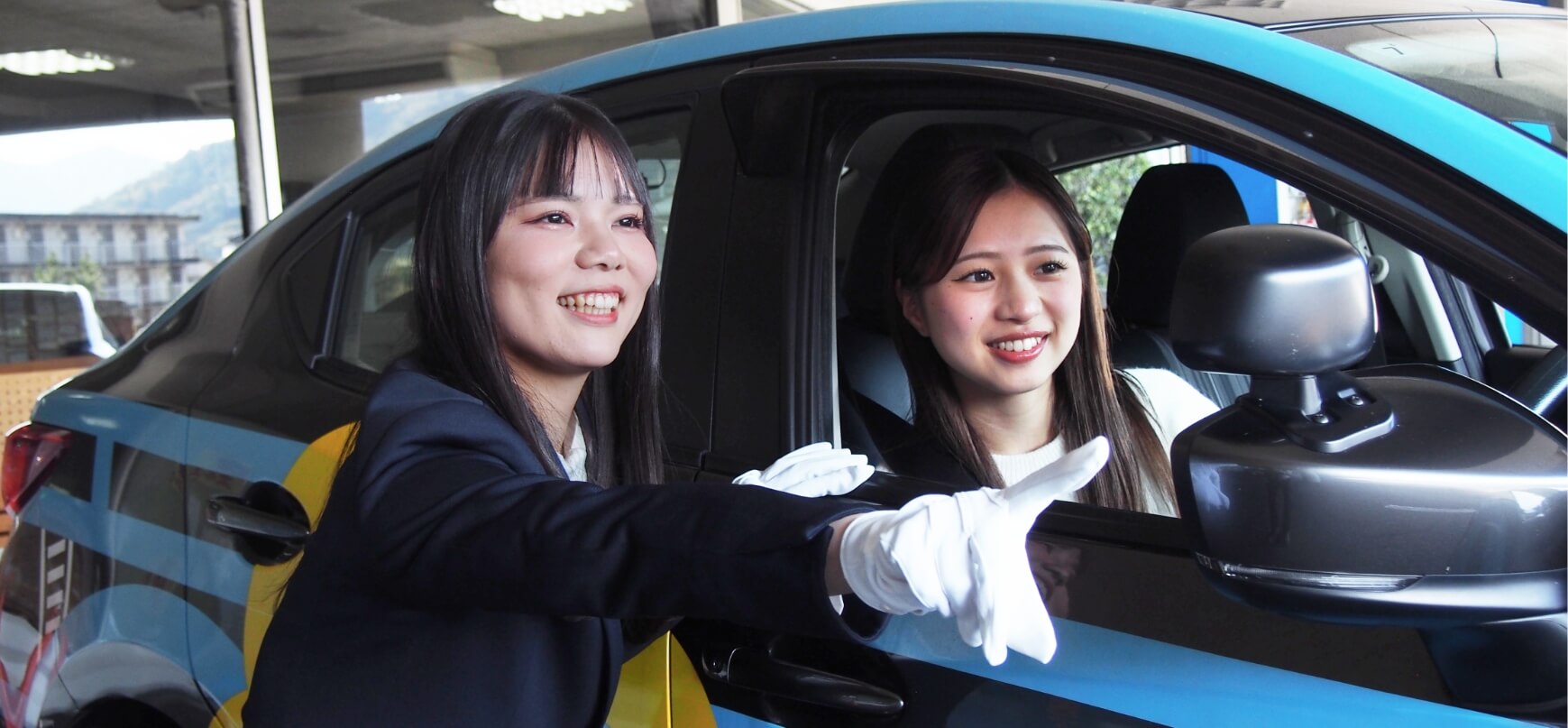 教習車の外で指導をする講師と、教習車の運転席に座っている在校生