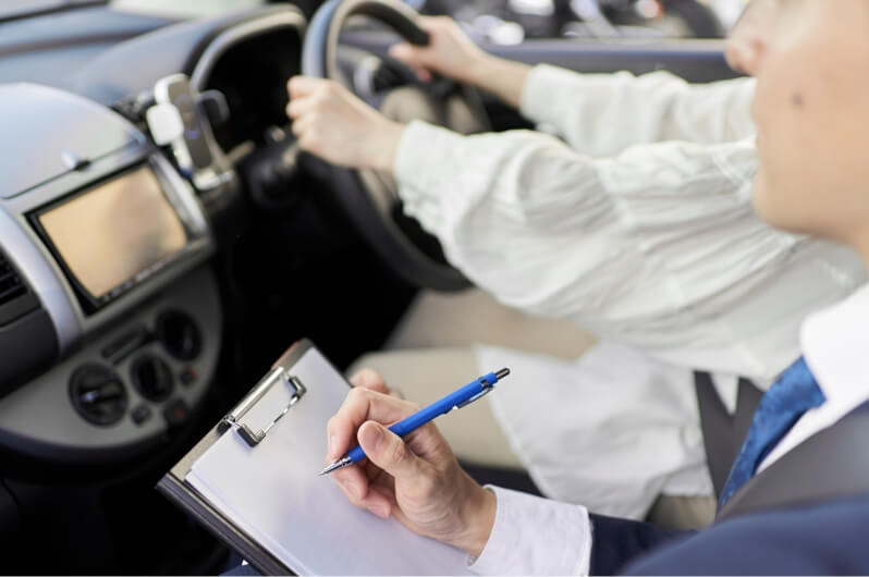 運転をしながら講習を受けている人と助手席でチェックしている講師